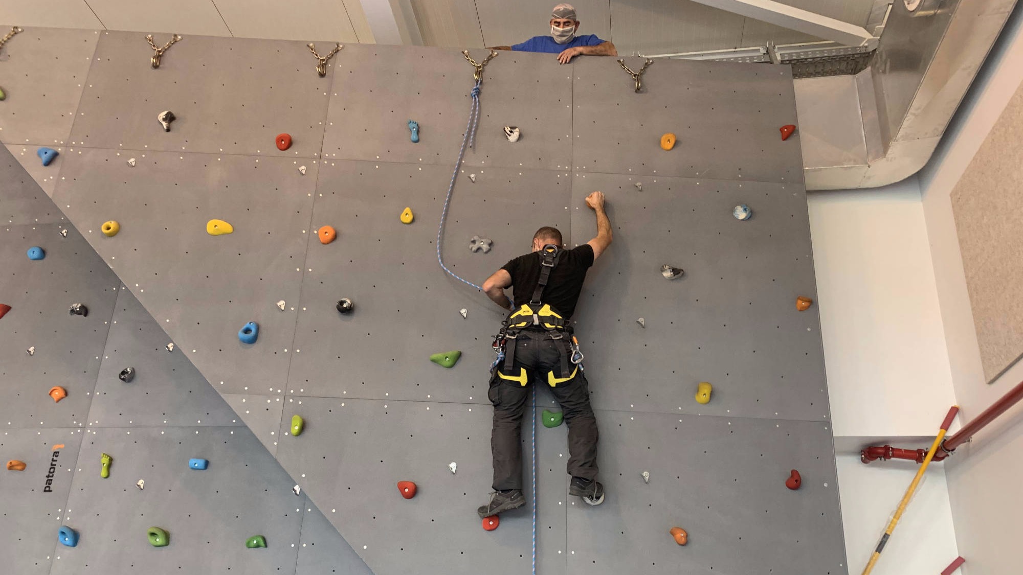 Técnico a realizar manutenção de parede de escalada